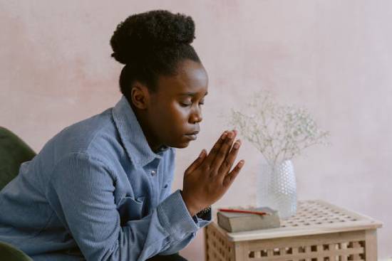 A Woman Praying After Bible Study A woman in a blue long-sleeved shirt praying after studying the word of God.
