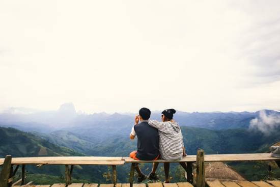 A Couple Sitting on a Bench on a Mountaintop A couple sitting on a bench on a mountaintop and enjoying a beautiful view.