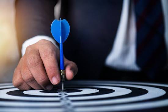 Goal Setting A person holding a blue dart pin setting their targets.