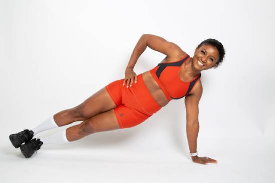 Woman Doing a Side Plank A woman in an orange fitness gear doing a side plank.