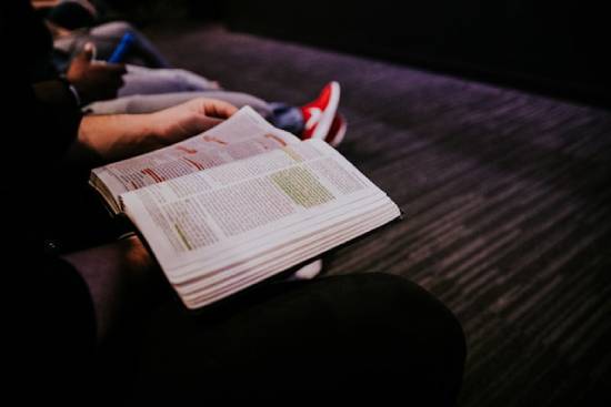 A person reading and highlighting his Bible with a highlighter.