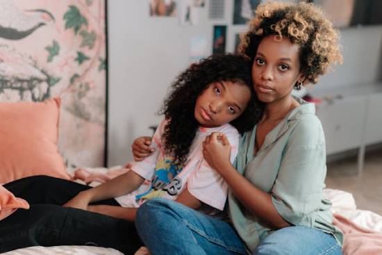 A crying mother holding and talking to her teenage daughter.