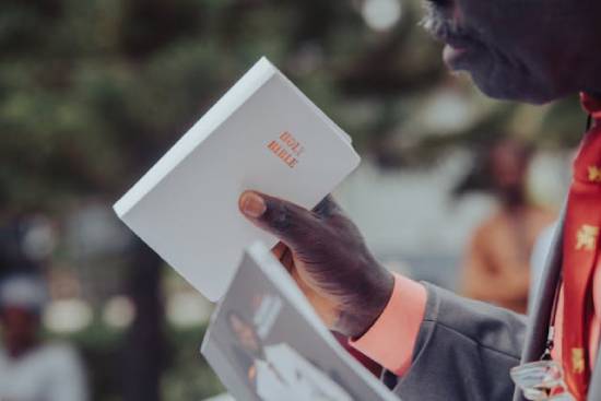 Preacher Lifting a Bible A preacherman lifting a white covered Holy Bible.