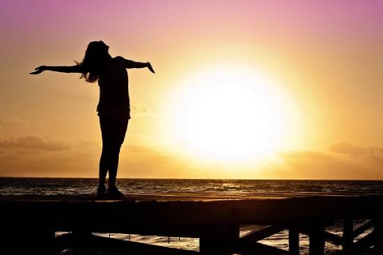 Silhouette of a happy woman spreading her arms during the golden hour.