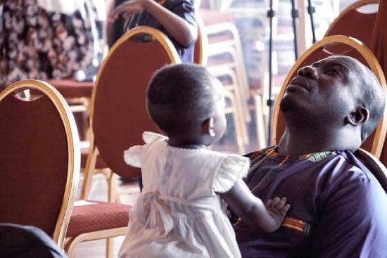 Single Father Praying A single father praying while carrying his daughter during a church service.