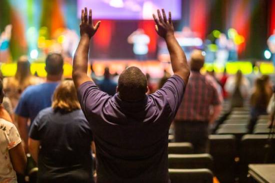 Man Lifting Hands in Prayer A man lifting both arms in prayer during a church service.