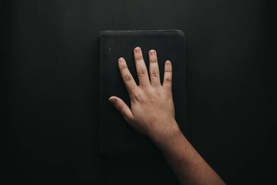 Man Holding Black Cover Bible A man holding a black cover Bible.