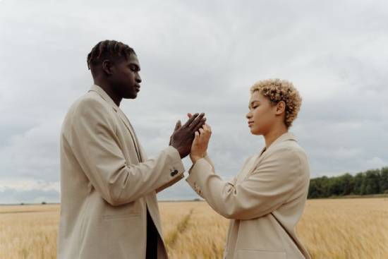 Couple Holding Hands and Conversing on a Field A couple in beige suits holding hands and having safe conversations in a grassfield.