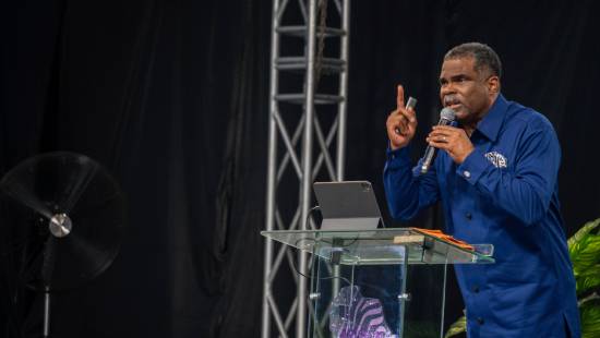 A preacher in a navy-blue top giving a sermon on divine delays.