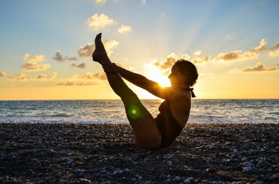 Woman Doing V-up Exercise A fitness enthusiast woman doing v-ups on a beach at sunset.